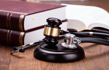 judge's gavel and stethoscope next to legal books