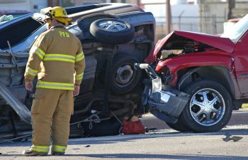 a firefighter next to two vehicles involved in a head-on collision