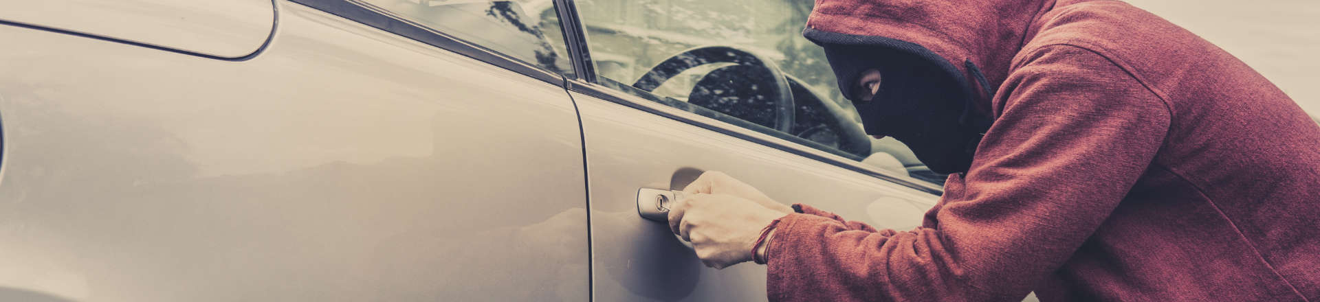 a man with covered face trying to break a car lock