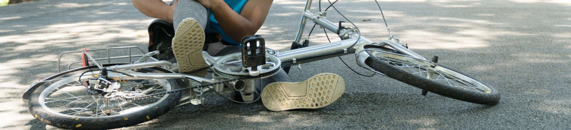 an injured cyclist sitting on the road next to their bike