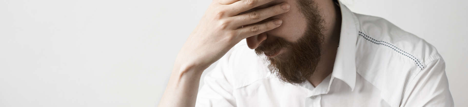 a depressed man leaning his forehead on his hand