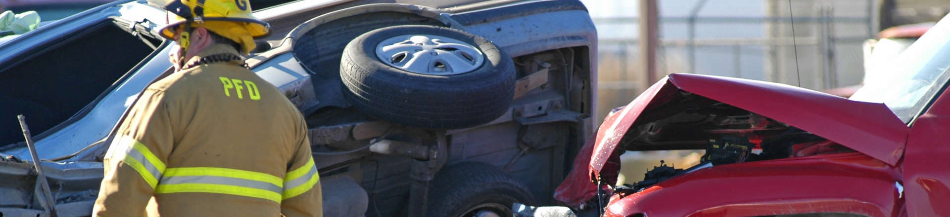 a firefighter next to two vehicles involved in a head-on collision