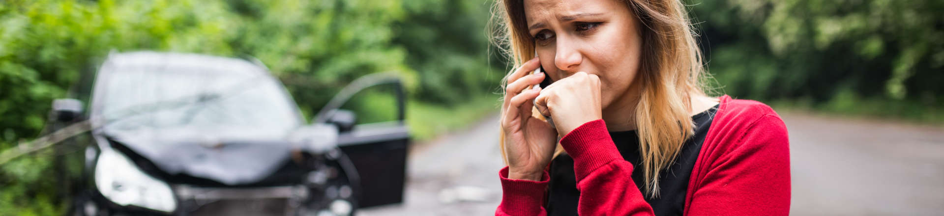 a stressed woman outside a crashed car talking on the phone