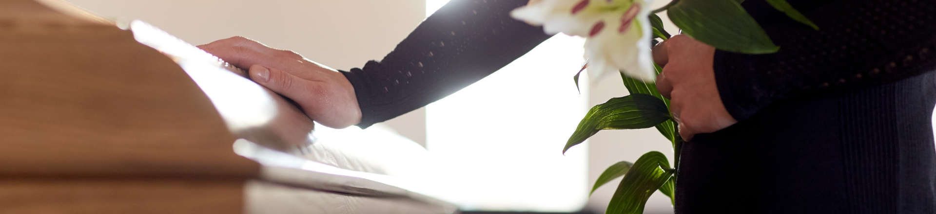 a person touching a coffin at a funeral ceremony
