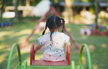 A little girl at a top of an outdoor slide.