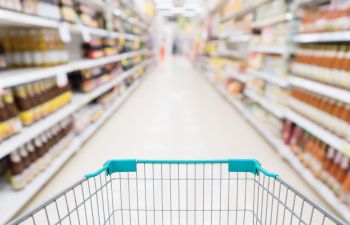 A shopping trolley in supermarket's aisle.