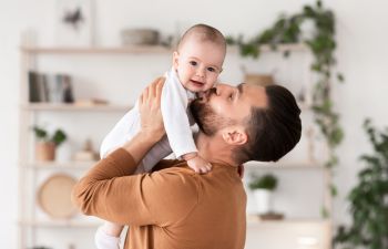 Father holding in arms and kissing his baby.